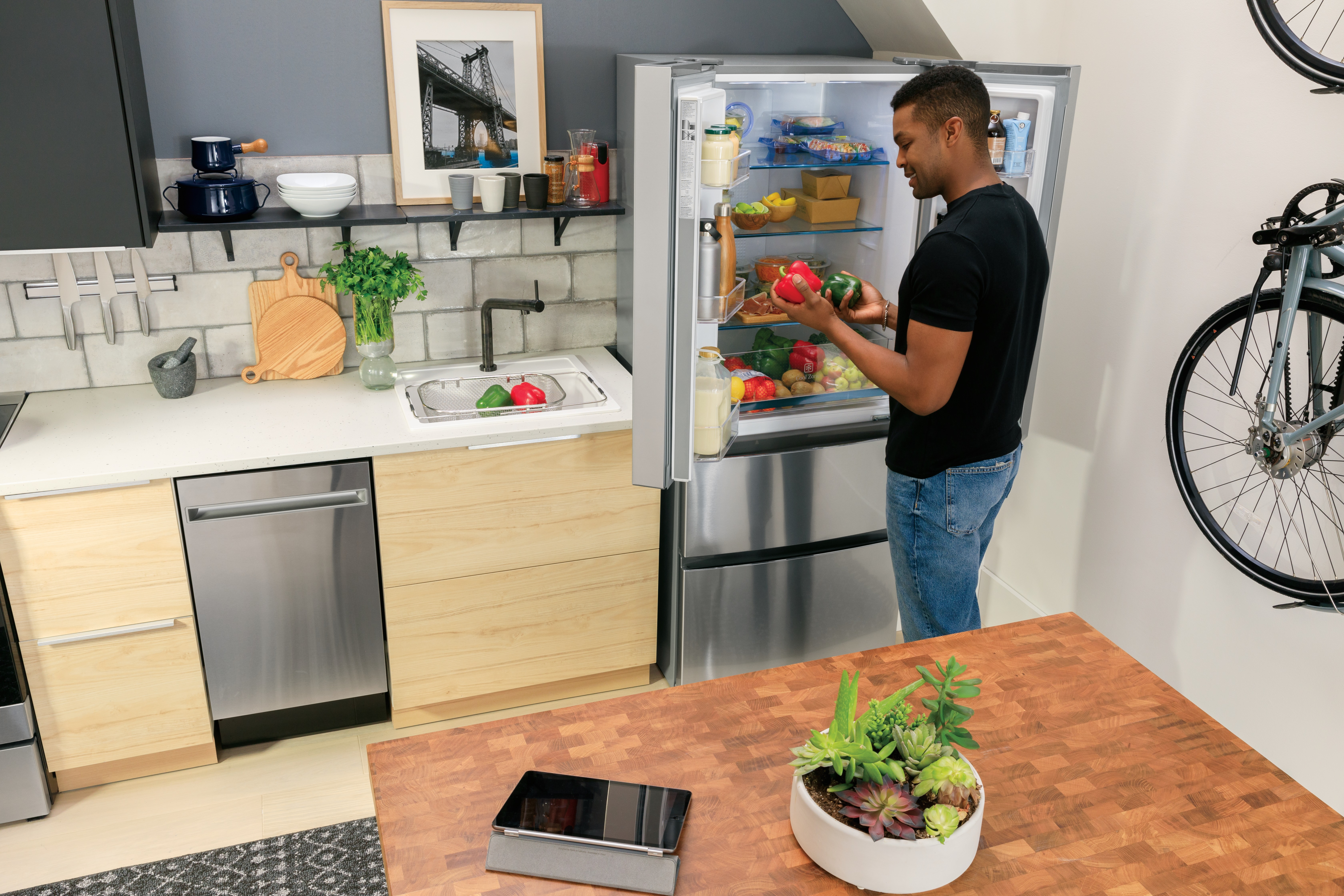 young man opens standard-depth Haier fridge in compact kitchen