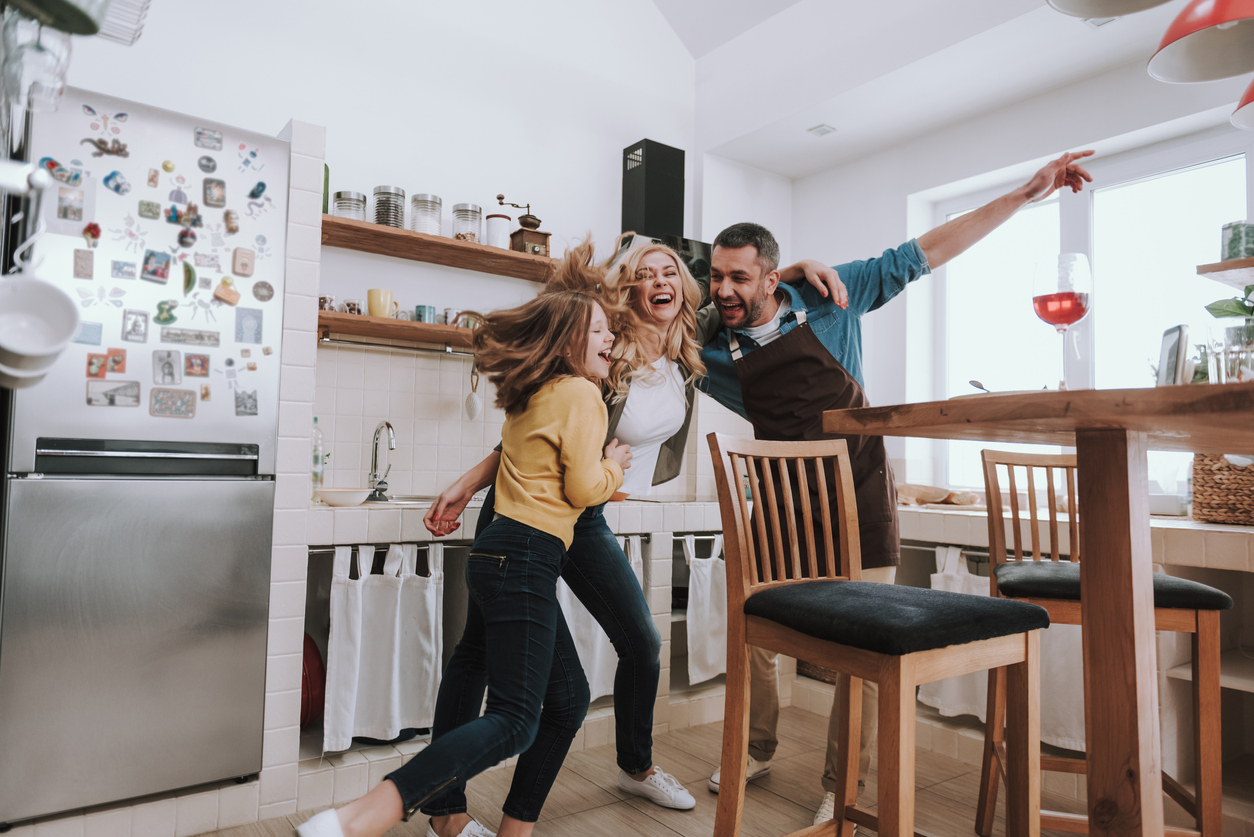 family dances in kitchen in front of bottom freezer refrigerator