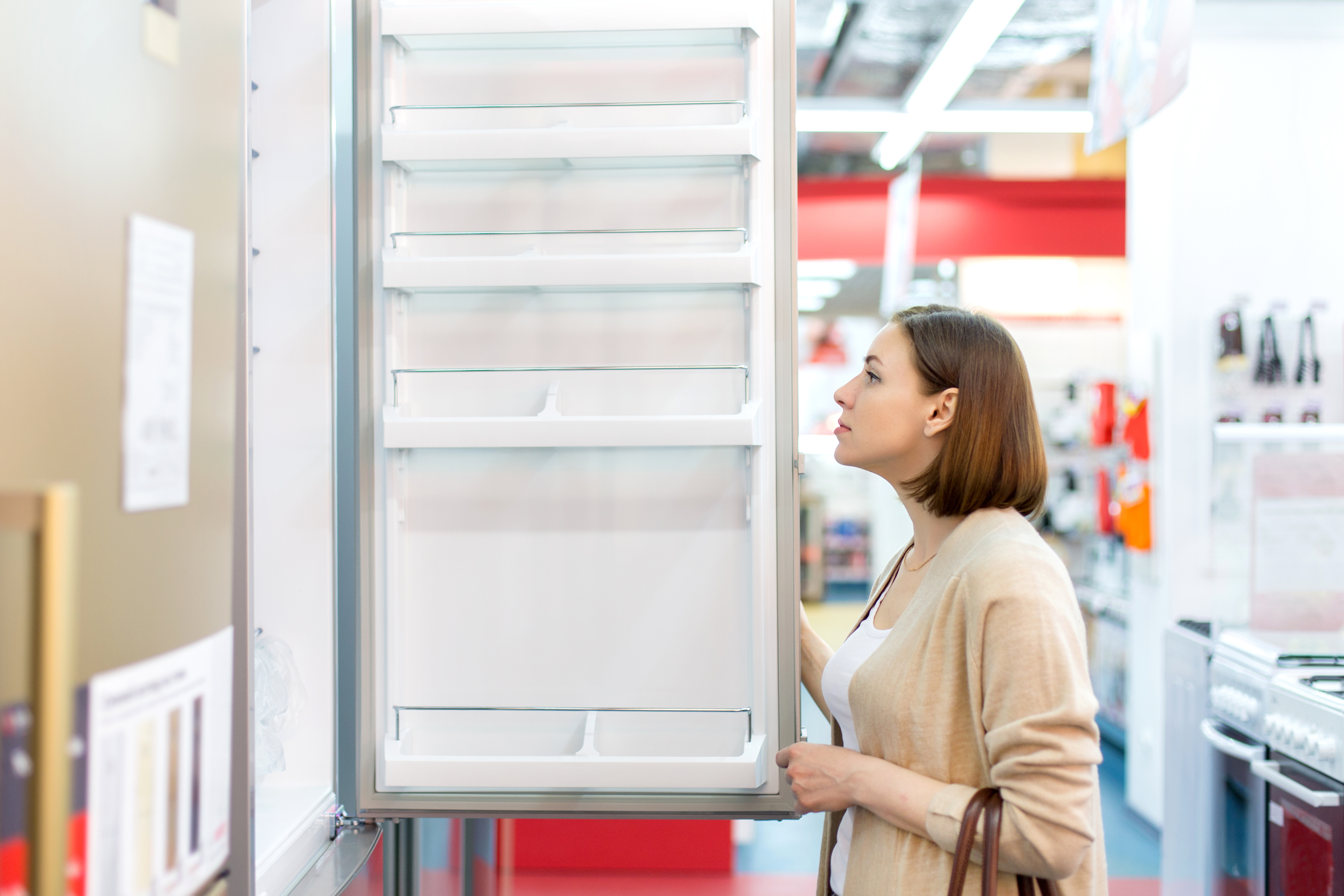 Woman in an appliance store reviewing the inside of a refrigerator