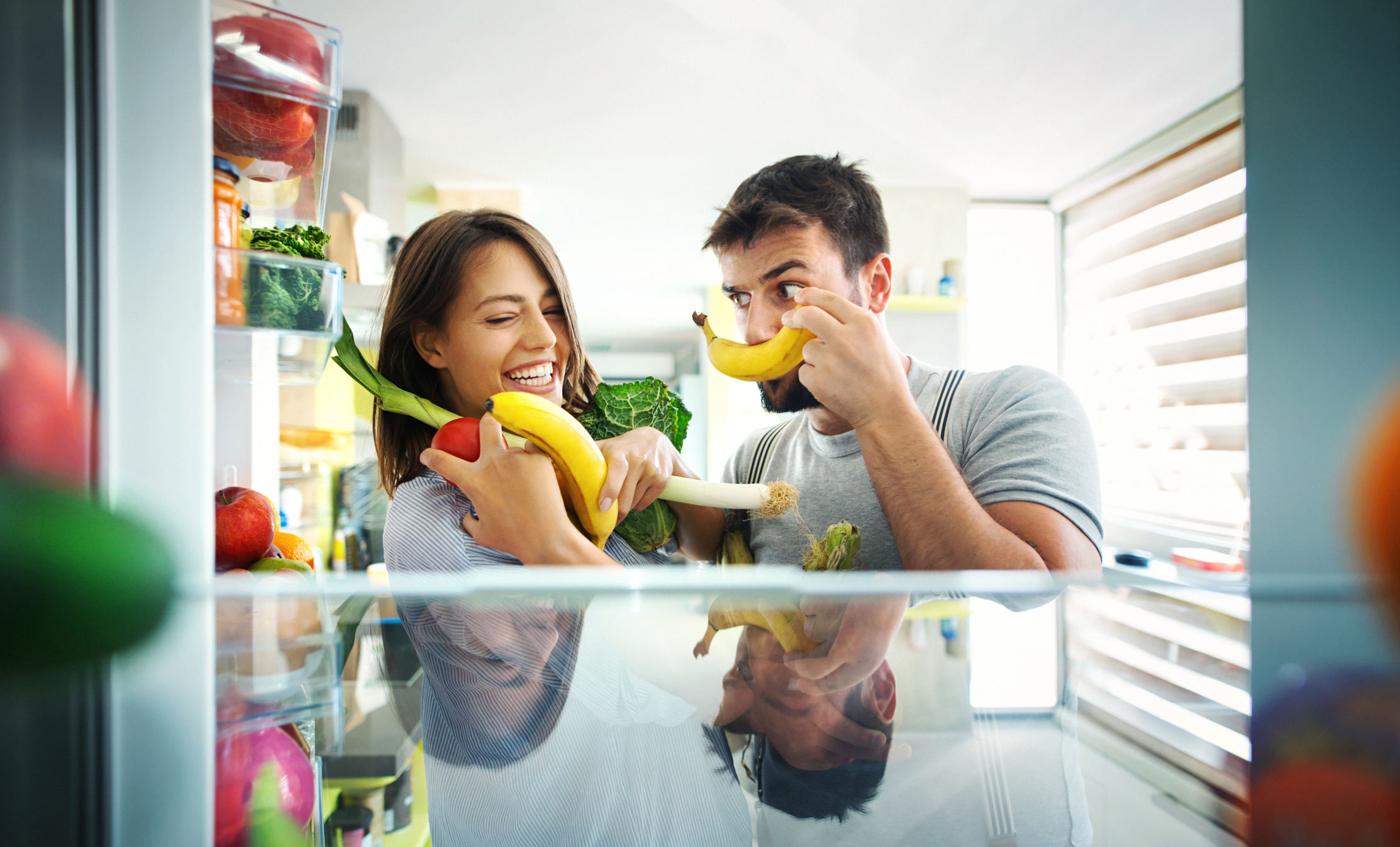 laughing couple taking ingredients out of the fridge