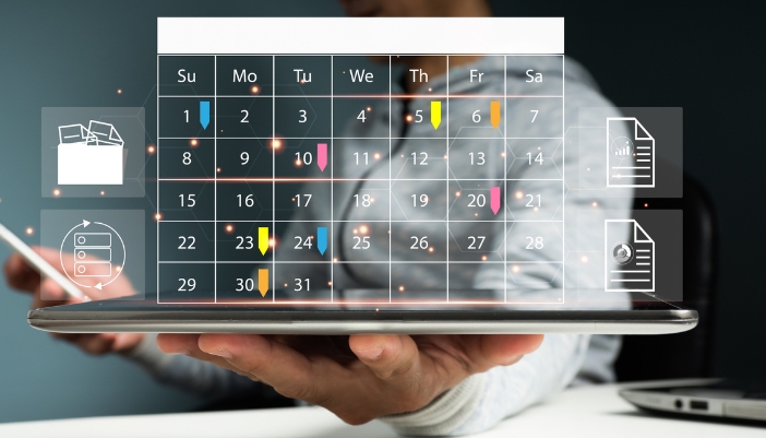 A closeup of someone’s busy caledar with events throughout the month hovering over a tablet