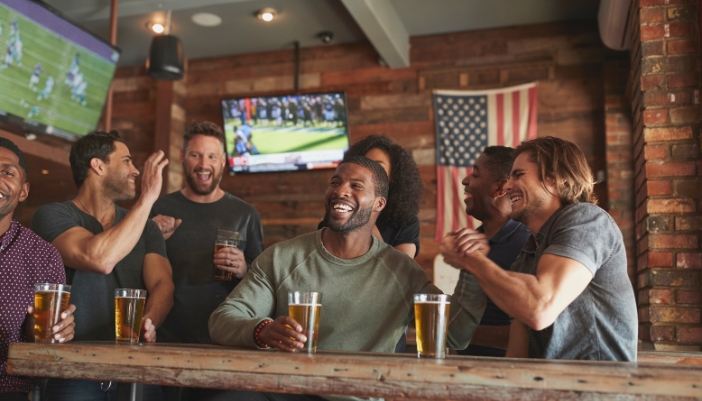 Friends enjoying game at sports bar with multiple screens showing different things and a good audio system