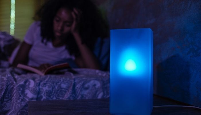 young woman reading next to blue lights 