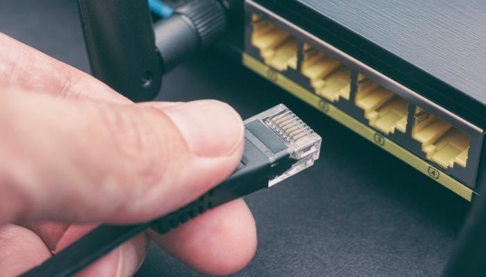 person plugging ethernet cable in to wireless router
