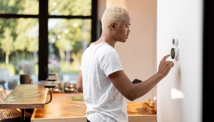 man choosing temperature on smart thermostat