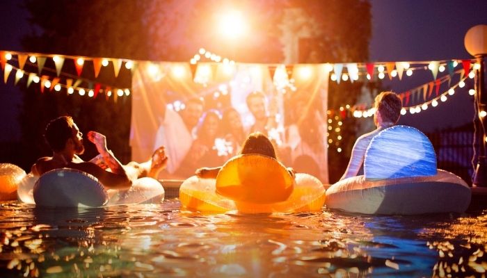 people watching movie under lights in pool