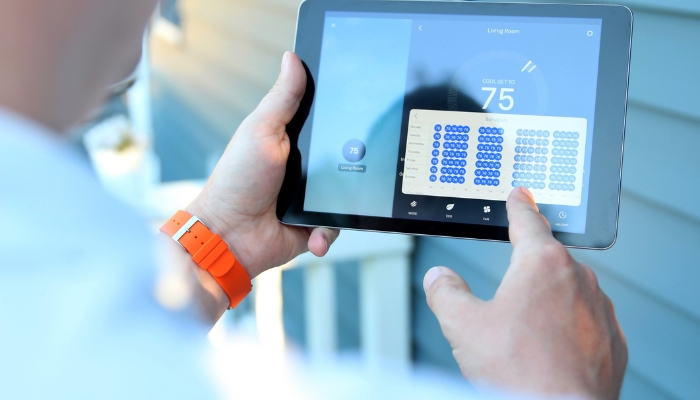 Closeup of man adjusting smart thermostat from tablet