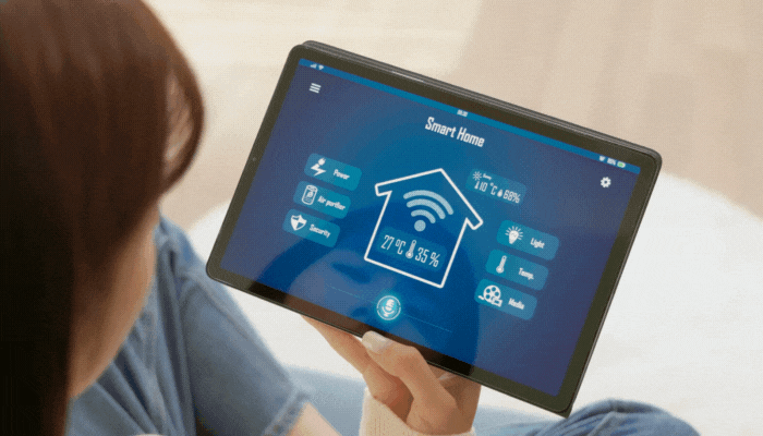 Woman using smart tablet and voice commands to lower temperature and see the energy usage on her device