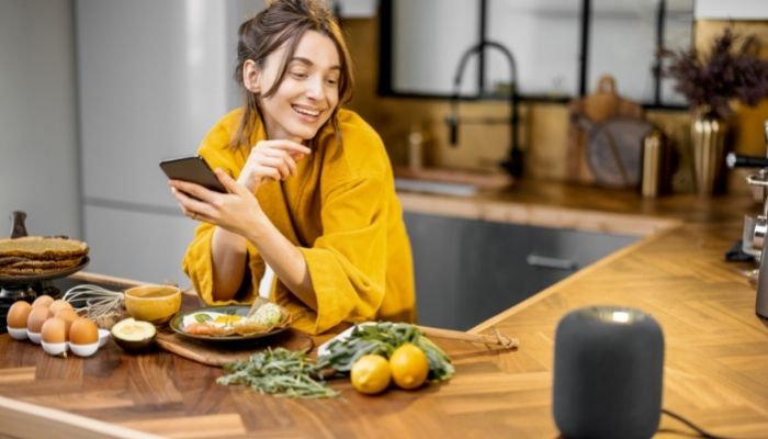 Woman using voice commands in the kitchen with smart speaker