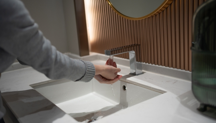 Woman using touchless faucet in luxury bathroom