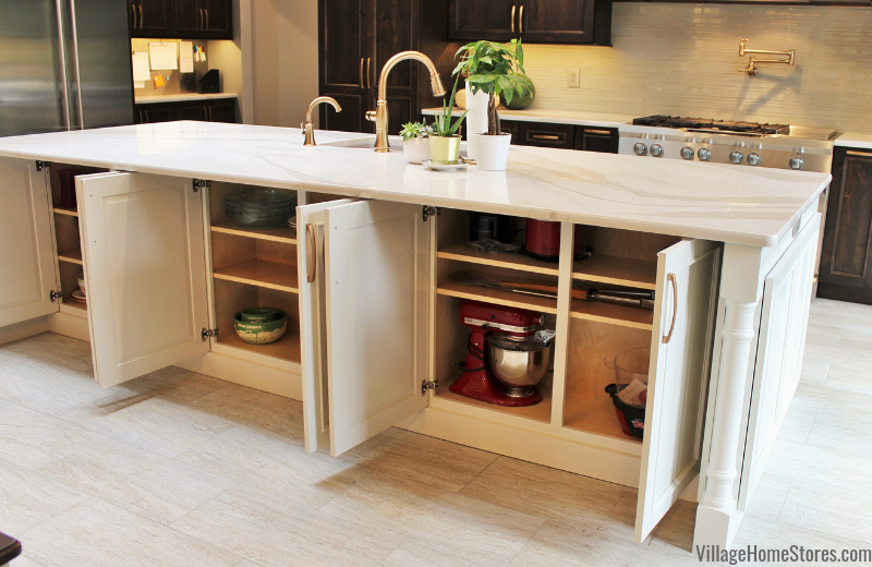 Back of kitchen island underneath countertop overhang with doors open to showcase available storage.