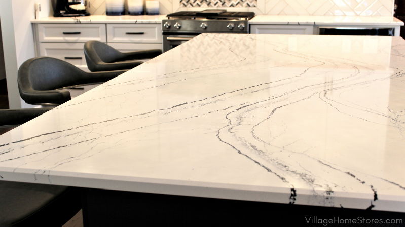 Kitchen island countertop in engineered Cambria Quartz Portrush. White marble look design with blue veining pattern.