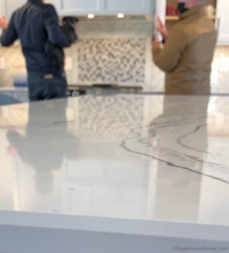 Quartz kitchen countertop edge with two men blurred in background discussing remodel