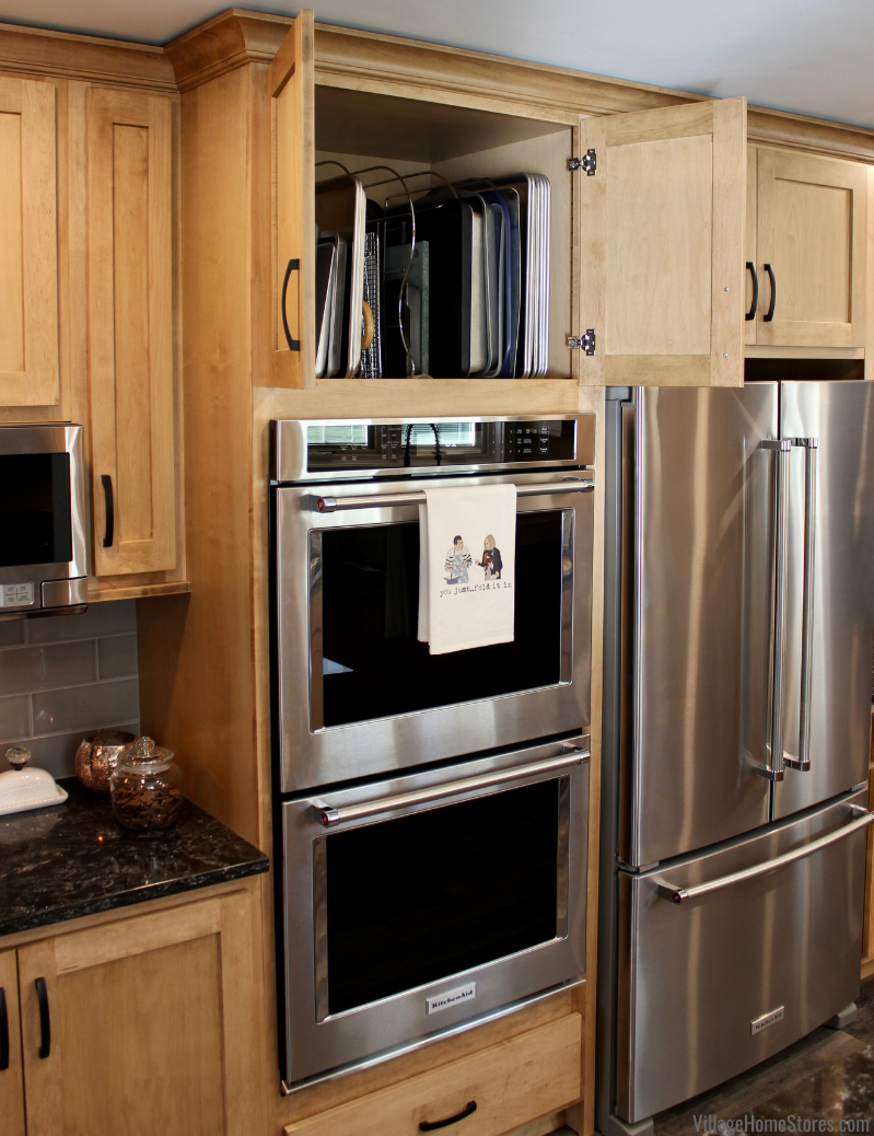 Image of double stainless steel wall ovens with open cabinet doors above. Tray dividers inside of upper cabinet for organizing baking sheets and racks