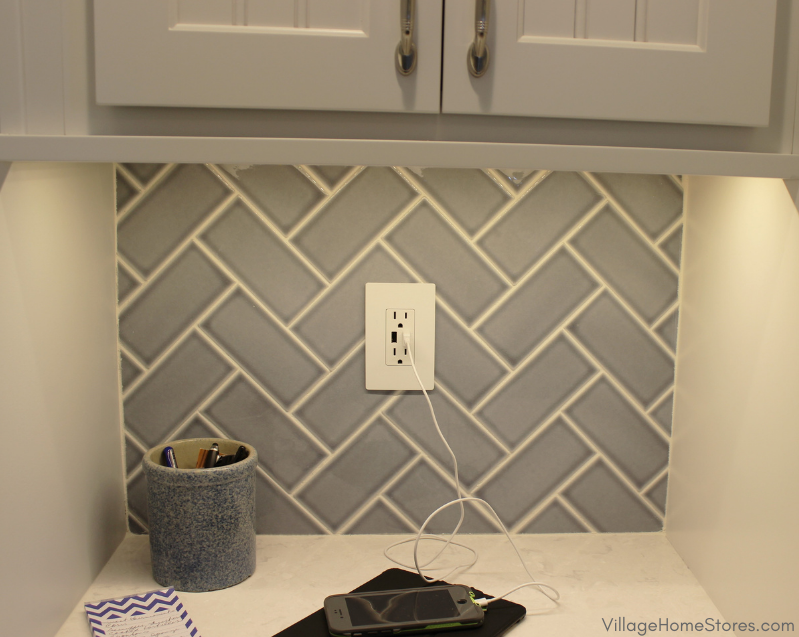 Blue subway tile installed with white grout in a herringbone pattern