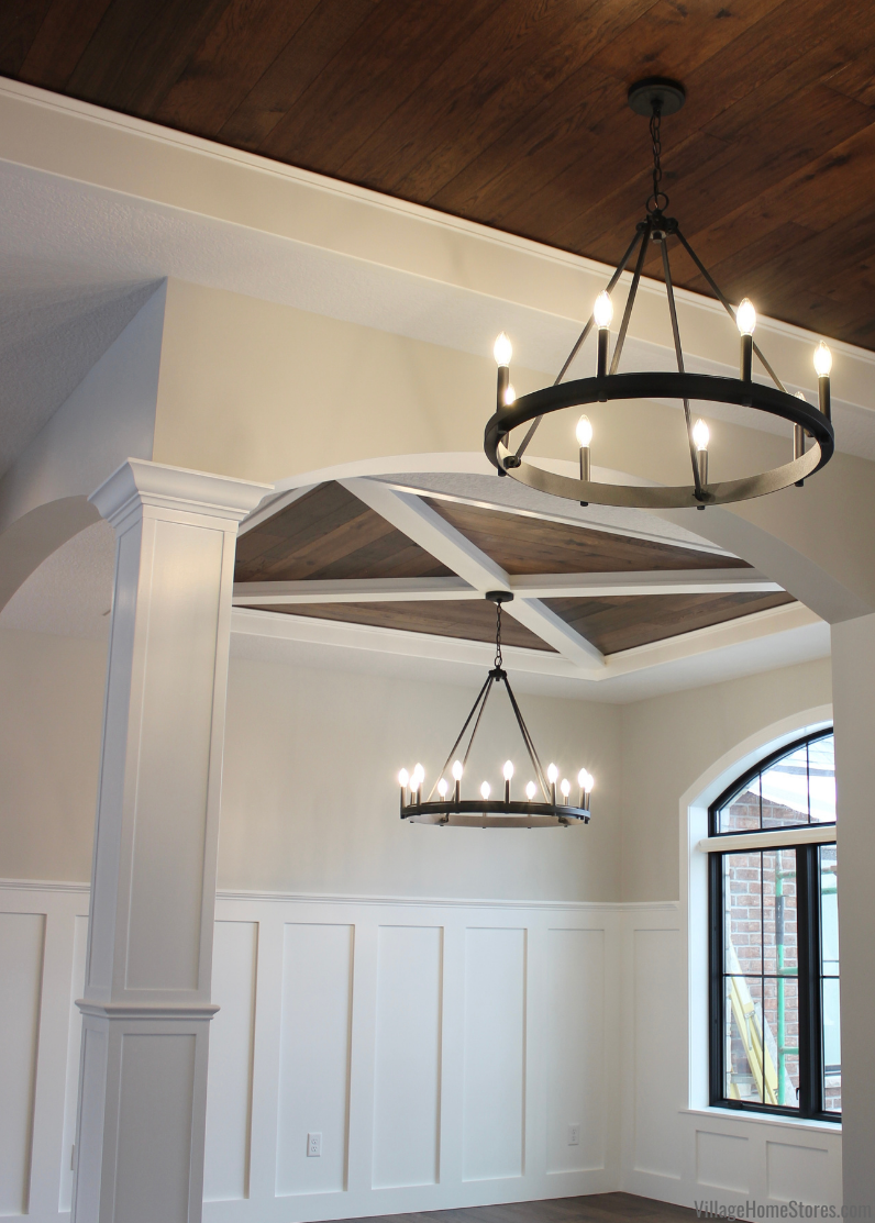 Quorum black circle chandeliers hanging in foyer and dining room of new home with X and wood ceiling detail.