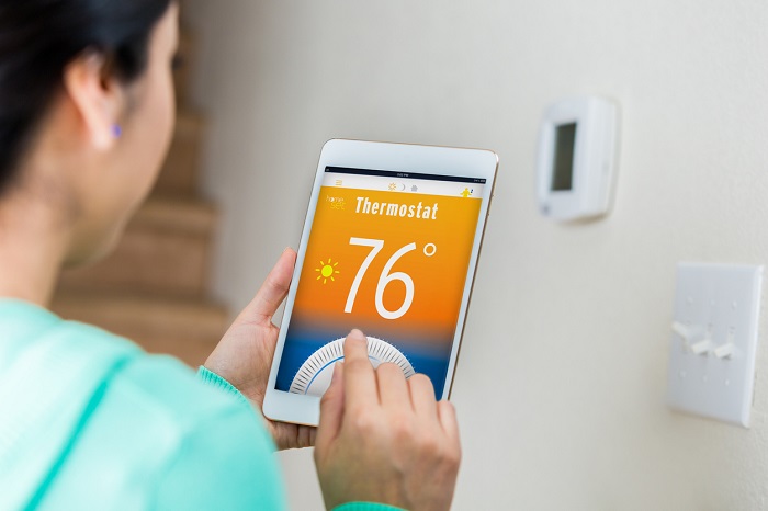 Female homeowner uses technology on digital tablet to control her home's temperature remotely.