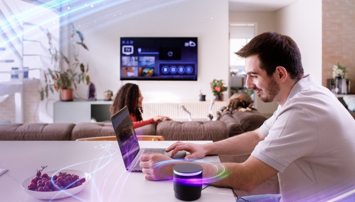 Concept photo of a couple using the bandwidth on their TV, laptop, and voice assistant