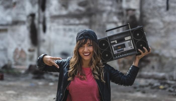 Woman holding boombox with smile and peace sign