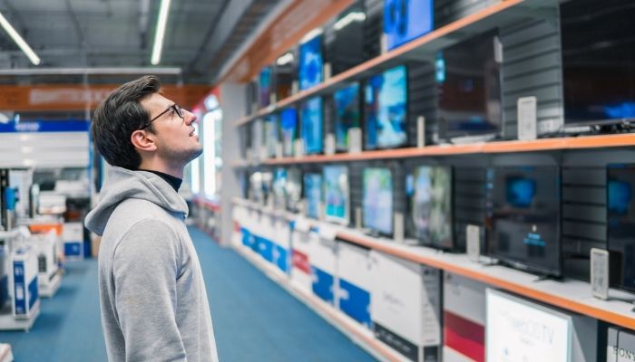 Man in electronics store looking at TVs