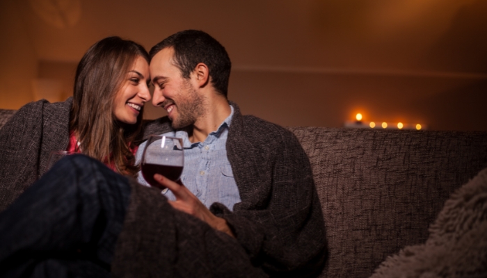 Couple getting cozy on date night with wine and a blanket