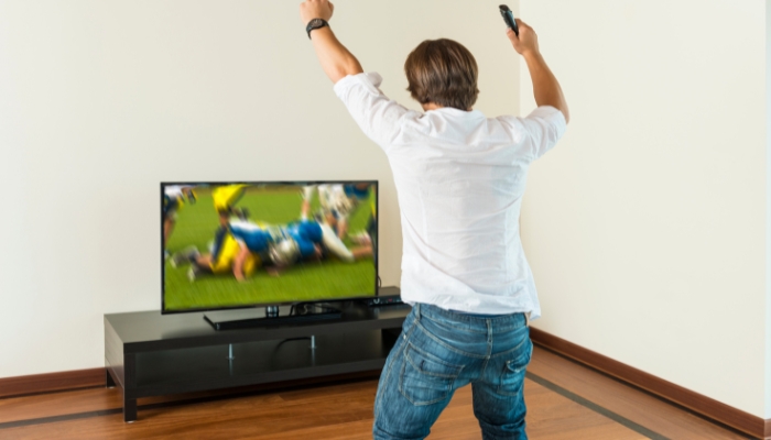 Man cheers on football team in front of his little TV setup