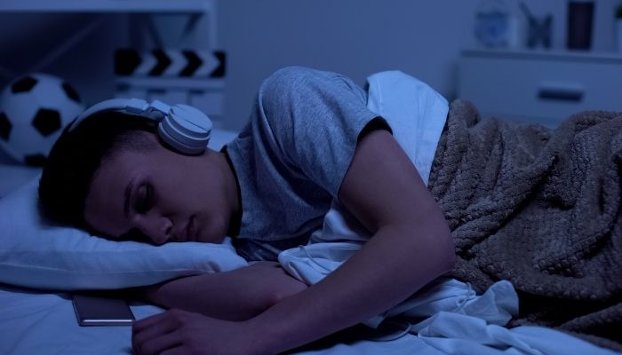 Teen sleeping with over-the-ear-headphones