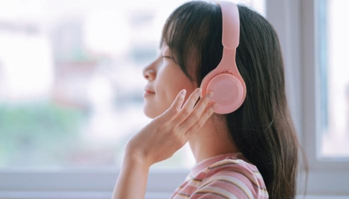 Woman listening to music on pink headphones