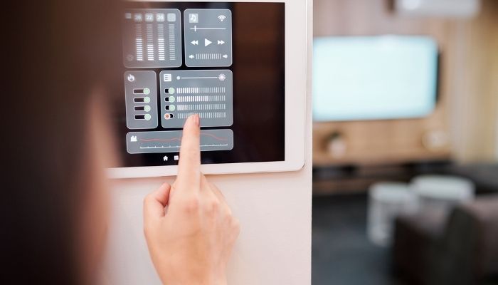 Hand touching digital buttons on smart remote control on the wall