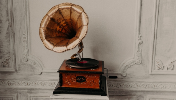 A vintage record player with a gramophone sits on a wooden table