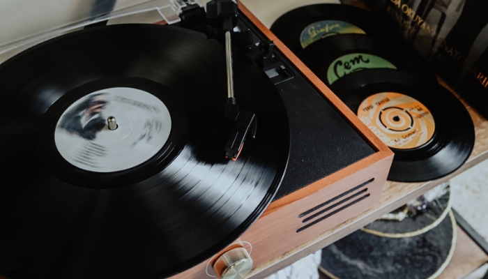 A black and brown record player sits on a table next to records out of their sleeves