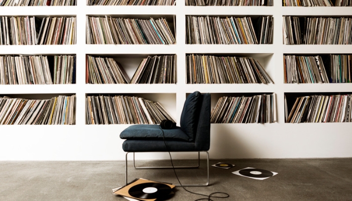 A gray chair with headphones on it sits in front of a wall of records