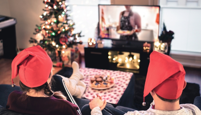 A couple watching baking program during the holidays on a large-screen TV