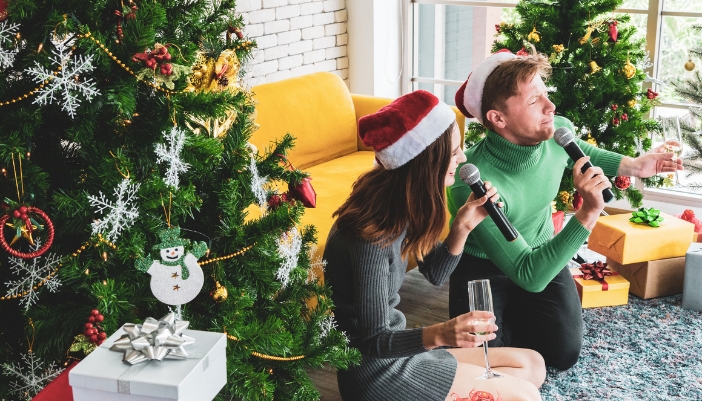 A couple doing karaoke by the Christmas tree