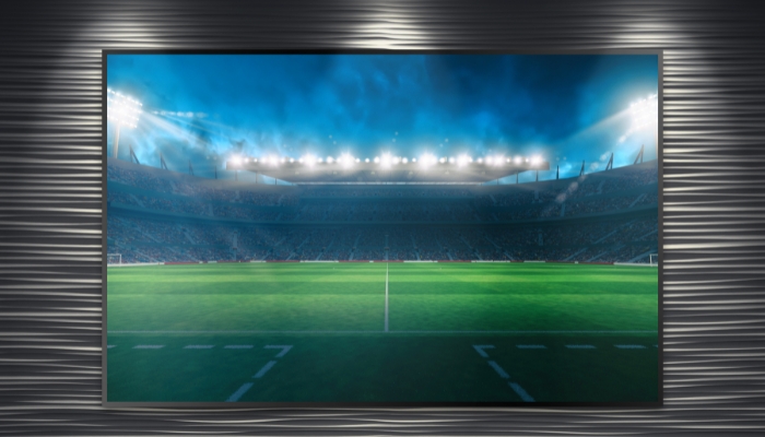  A large TV showing a football stadium is mounted on the wall