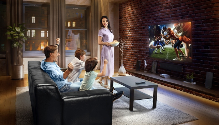 Family watching football with a soundbar and speakers