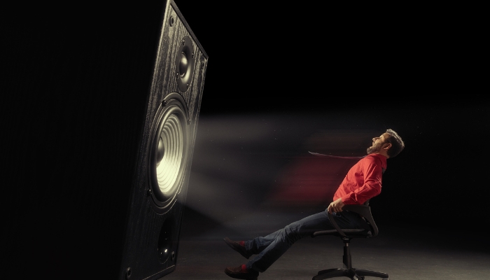Concept image of a man blown away by the quality of a giant hi-fi speaker