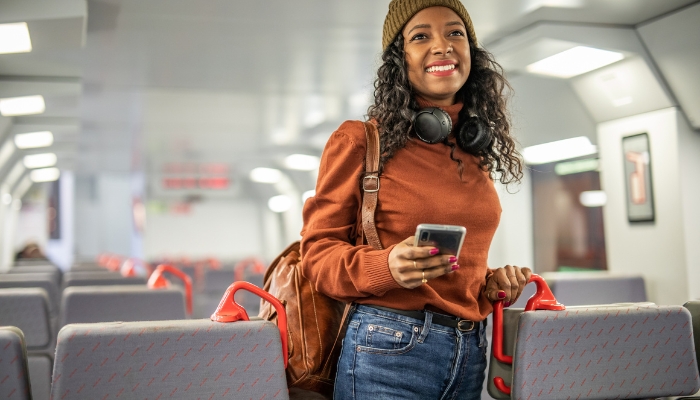 Woman on a Spanish train excited for her destination, wearing noise-canceling headphones