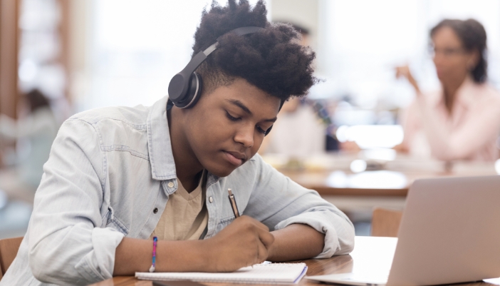 Young student listening to music while studying