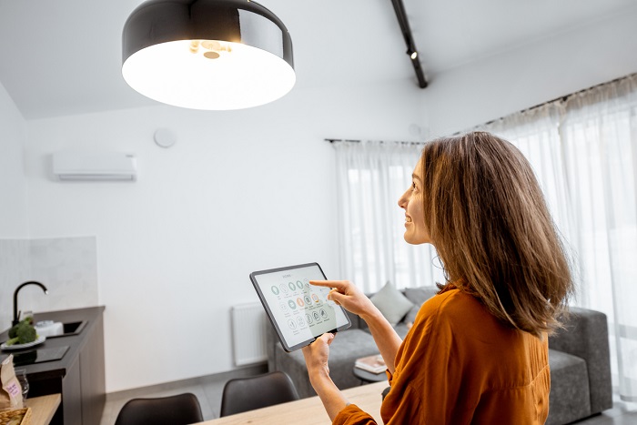 Young woman controlling home light with a digital tablet in the living room.