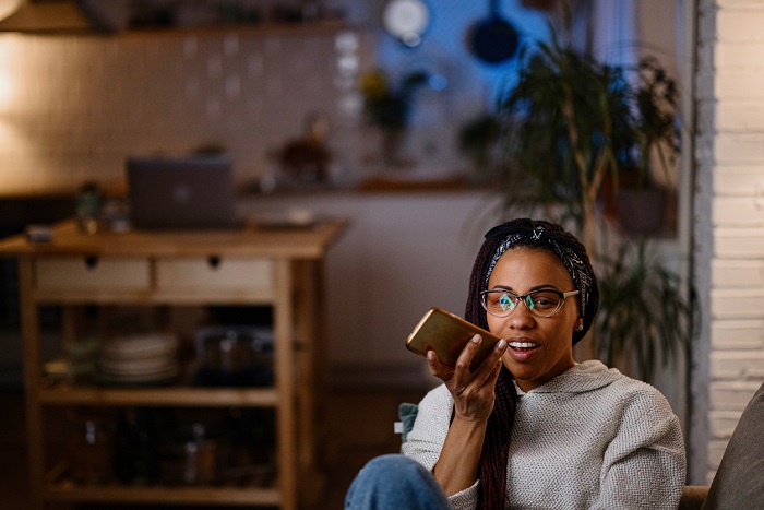 Woman speaking to her smart phone at home at night.