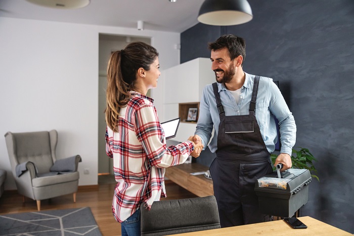 Happy woman shaking hands with a service technician