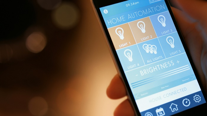 Hand holding a smart phone with a home automation screen focused on lighting.