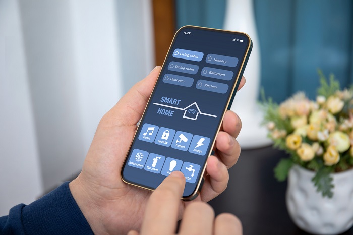 Hand holding smart phone with home automation app pulled up. 