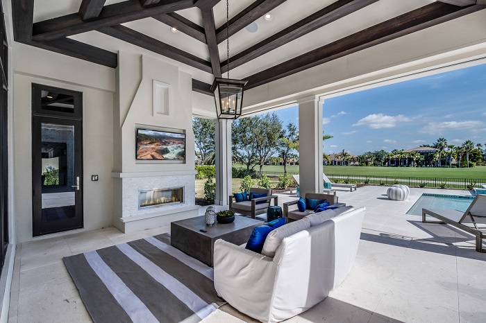 Luxurious, outdoor backyard on a golf course with outdoor TV and living furniture.