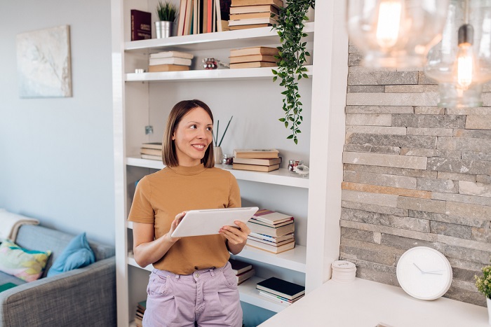 Young woman setting up the intelligent home system on a digital tablet.