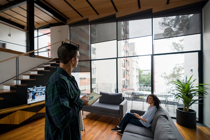 Happy couple controlling the settings of their smart home using a smart tablet. 