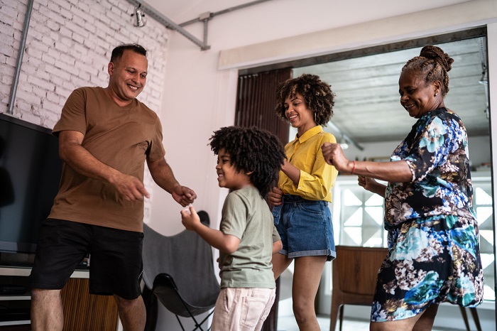 Multi generation family dancing at home to music. 