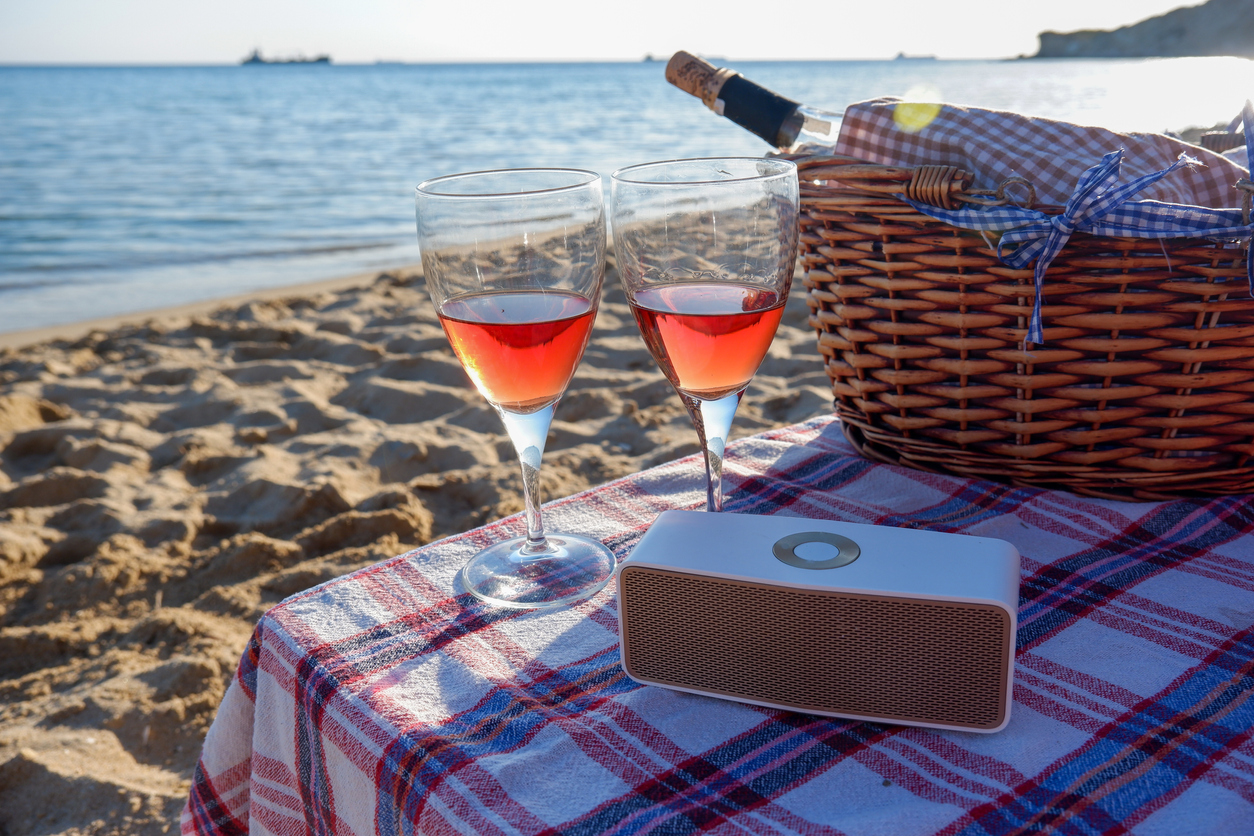 beachside portable speaker and picnic basket with wine bottle and glasses