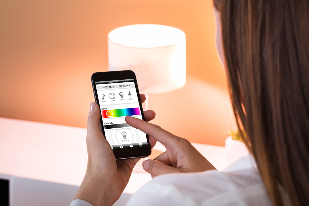 woman controls smart bulb with an app on her smartphone